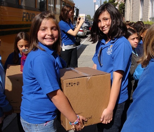 Student volunteers participating in community service work unload the books from their bus.
